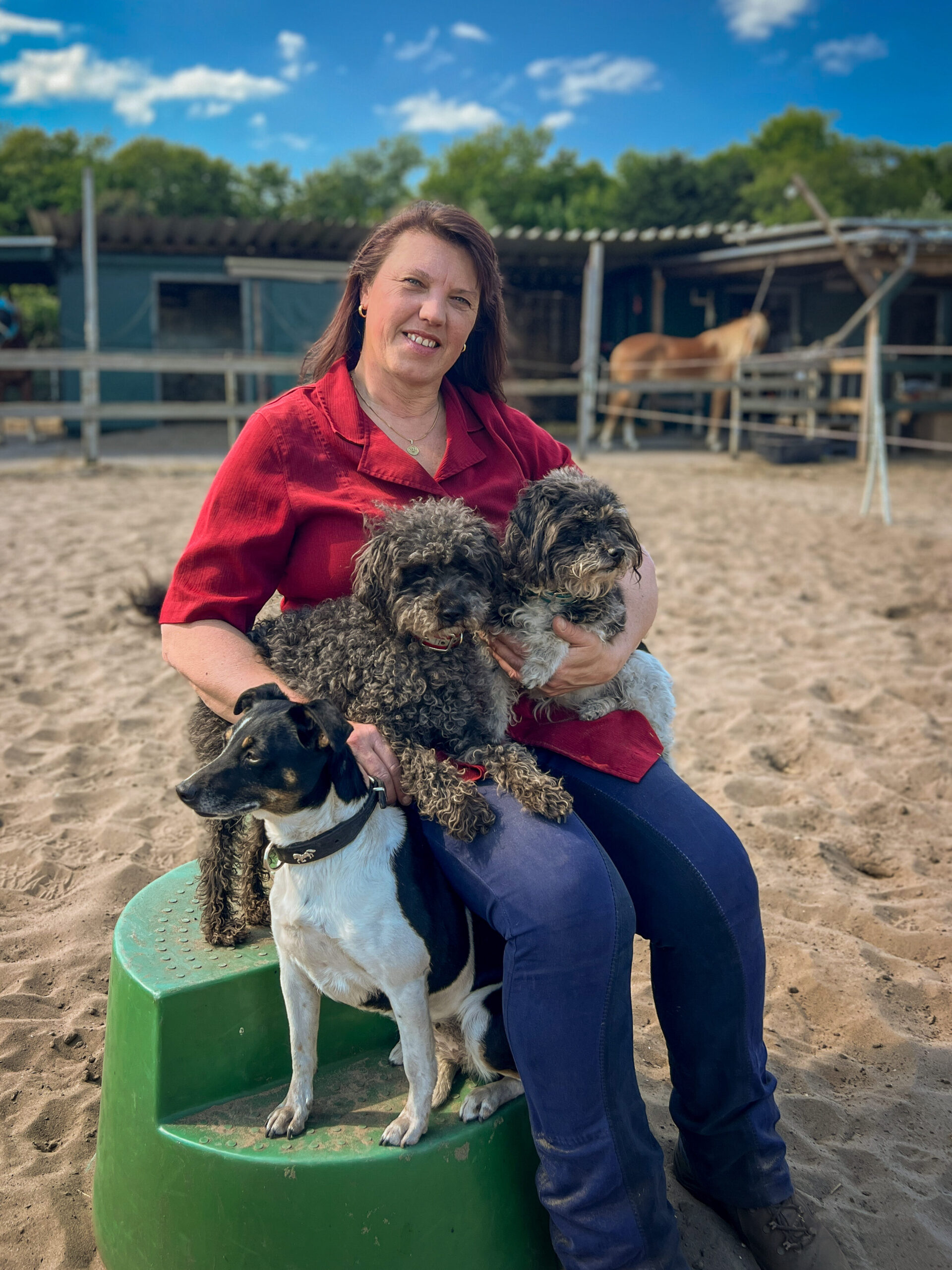 Portrait foto van paardencoach Carla Spaink met de honden op stal LC Ranch